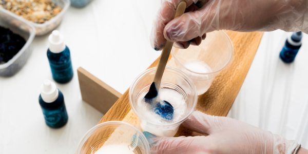artist stirring blue dye in a plastic cup with epoxy resin